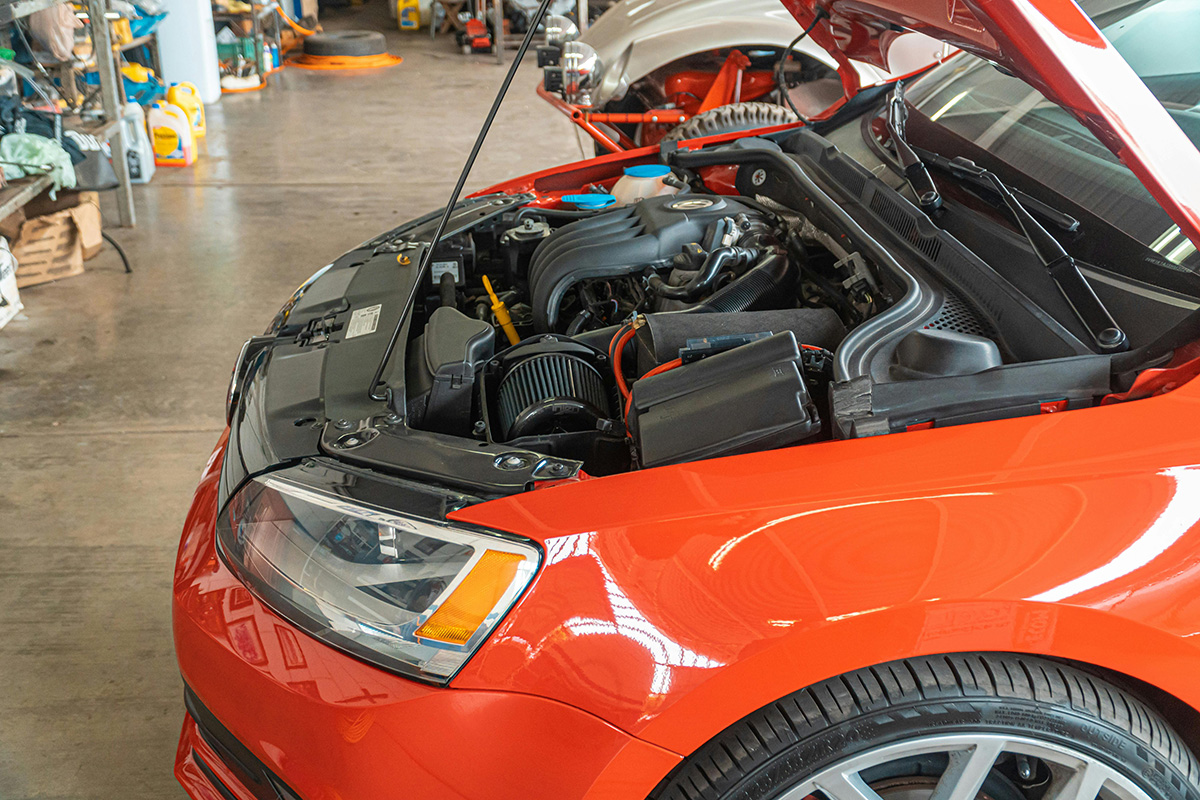 Red car in a body shop with its hood up