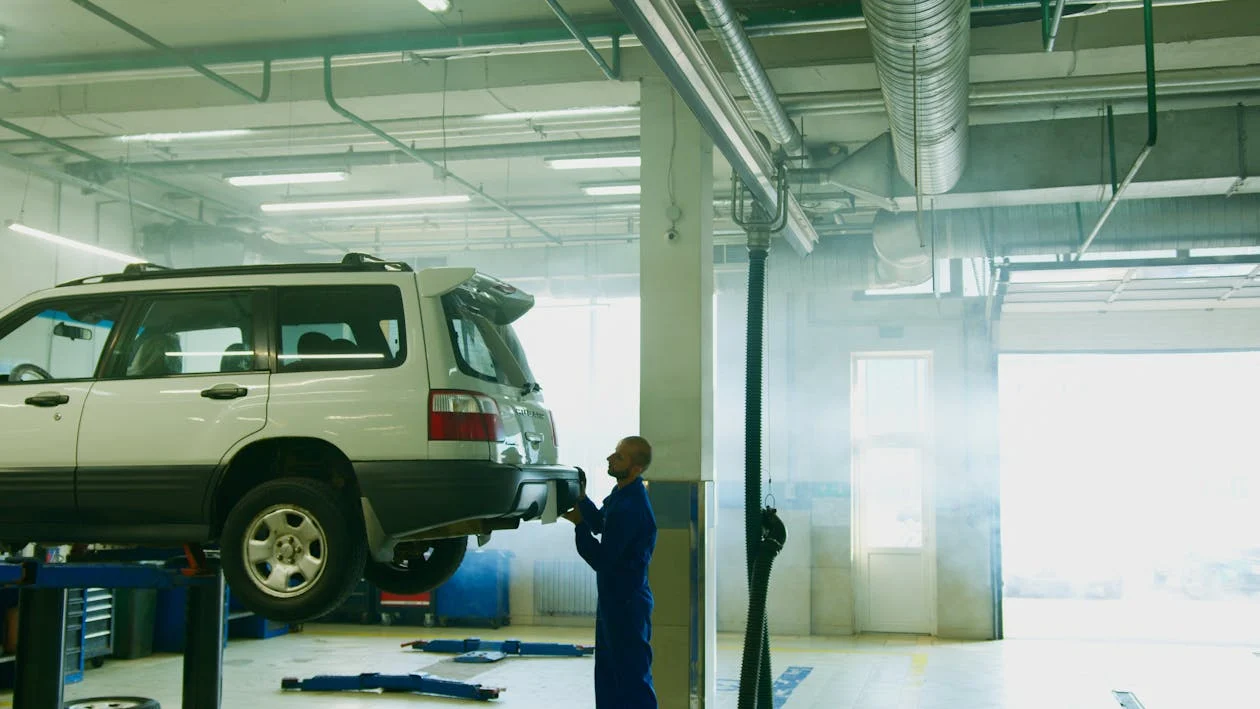 man holding the bumper of a car lifted in a repair shop