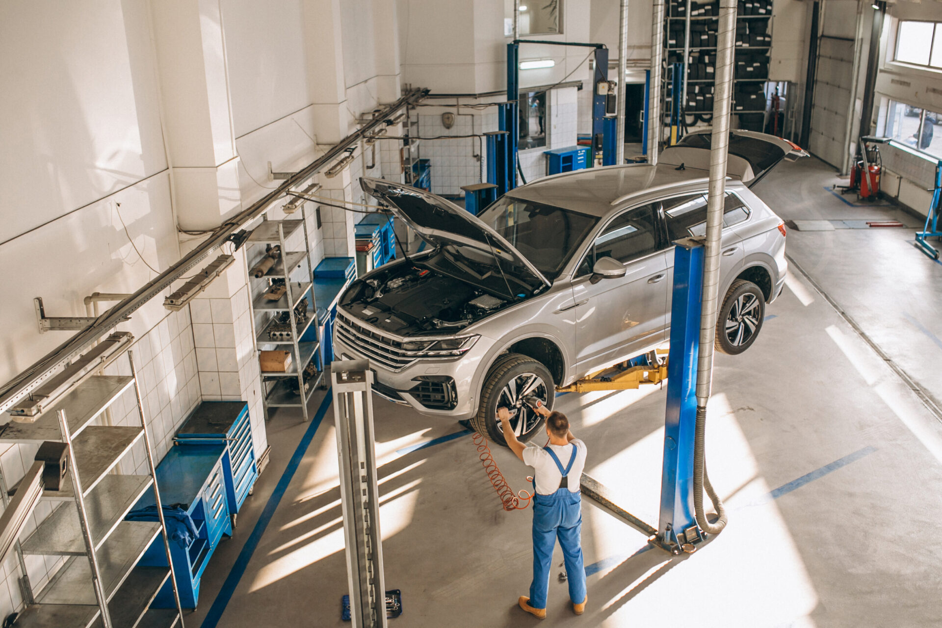 silver car on a lift in a body shop
