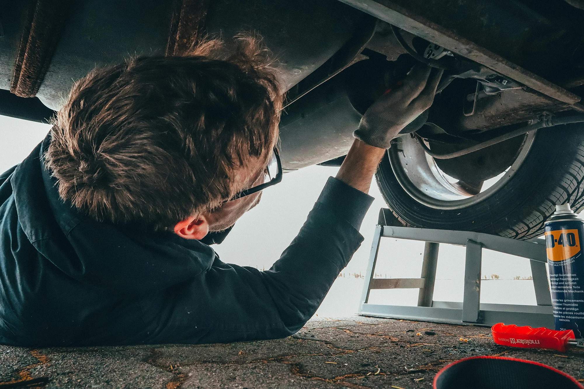 Man on the floor looking up to the underpart of a car.