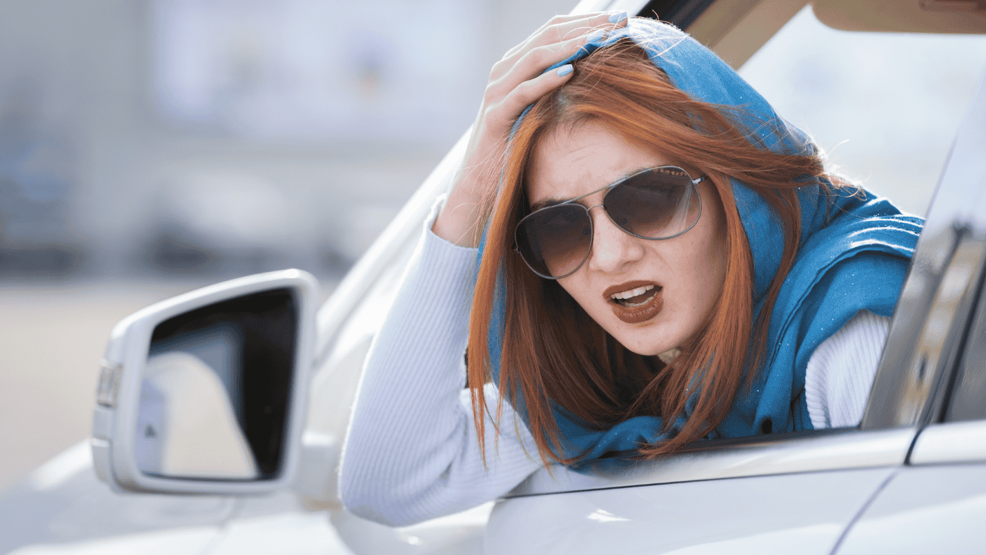 A woman looks out the window of her car in distress after a minor collision.