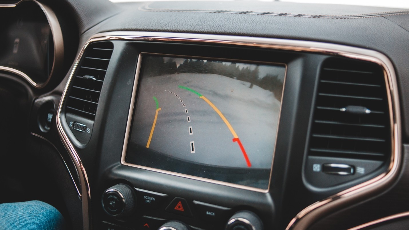 A car console screen shows an ADAS system assisting with reversing.