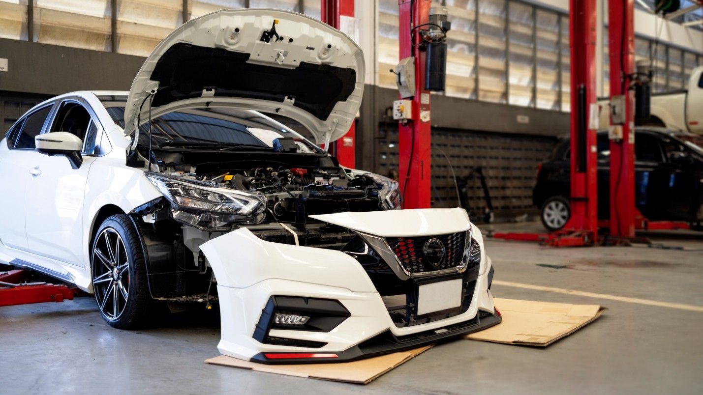 A car with an OEM bumper and grill waiting to be installed.