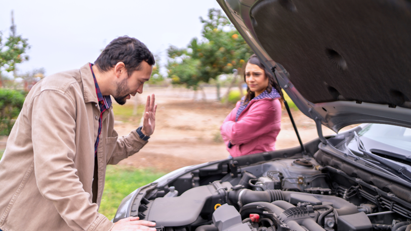 A man checks the engine of his car while pulled over on the side of the road.